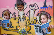 Natasha, Rushabh and Jade reading through the meerkat cutouts at Bristol Zoo Gardens.