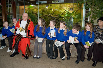 The Lord Mayor and Lady Mayoress of Bristol reading the books in the reptile house of Bristol Zoo Gardens with pupils from New Oak Primary.
